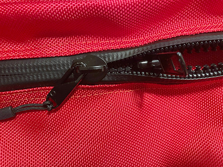 Close-up of the heavy-duty zipper on the red ballistic CollieBall cover